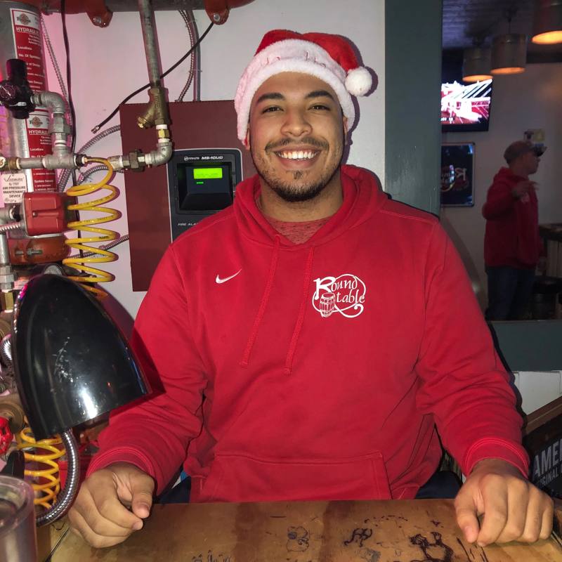 A bartender in a Santa hat and Round Table hoodie