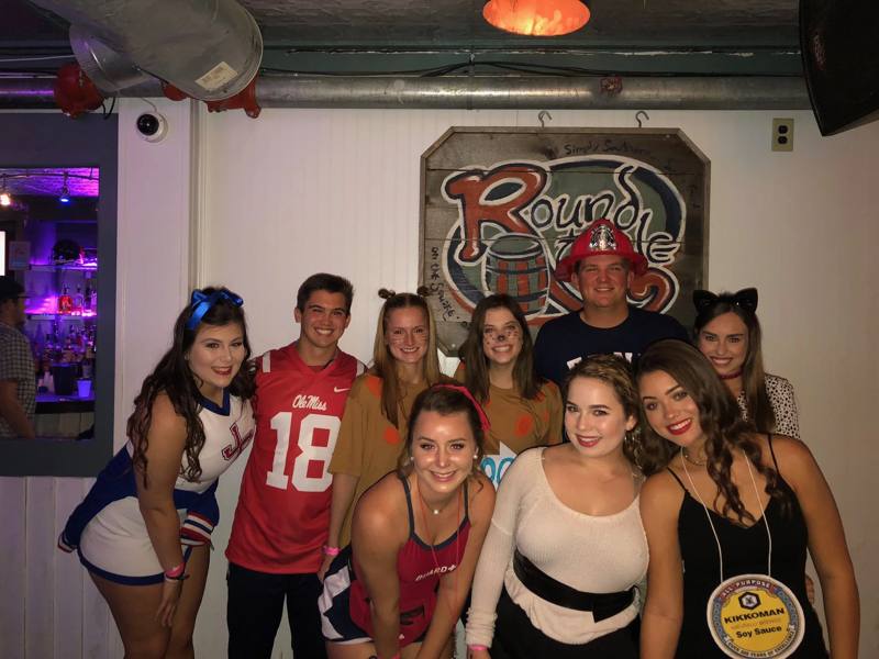 A costumed crew under the Round Table sign on Halloween
