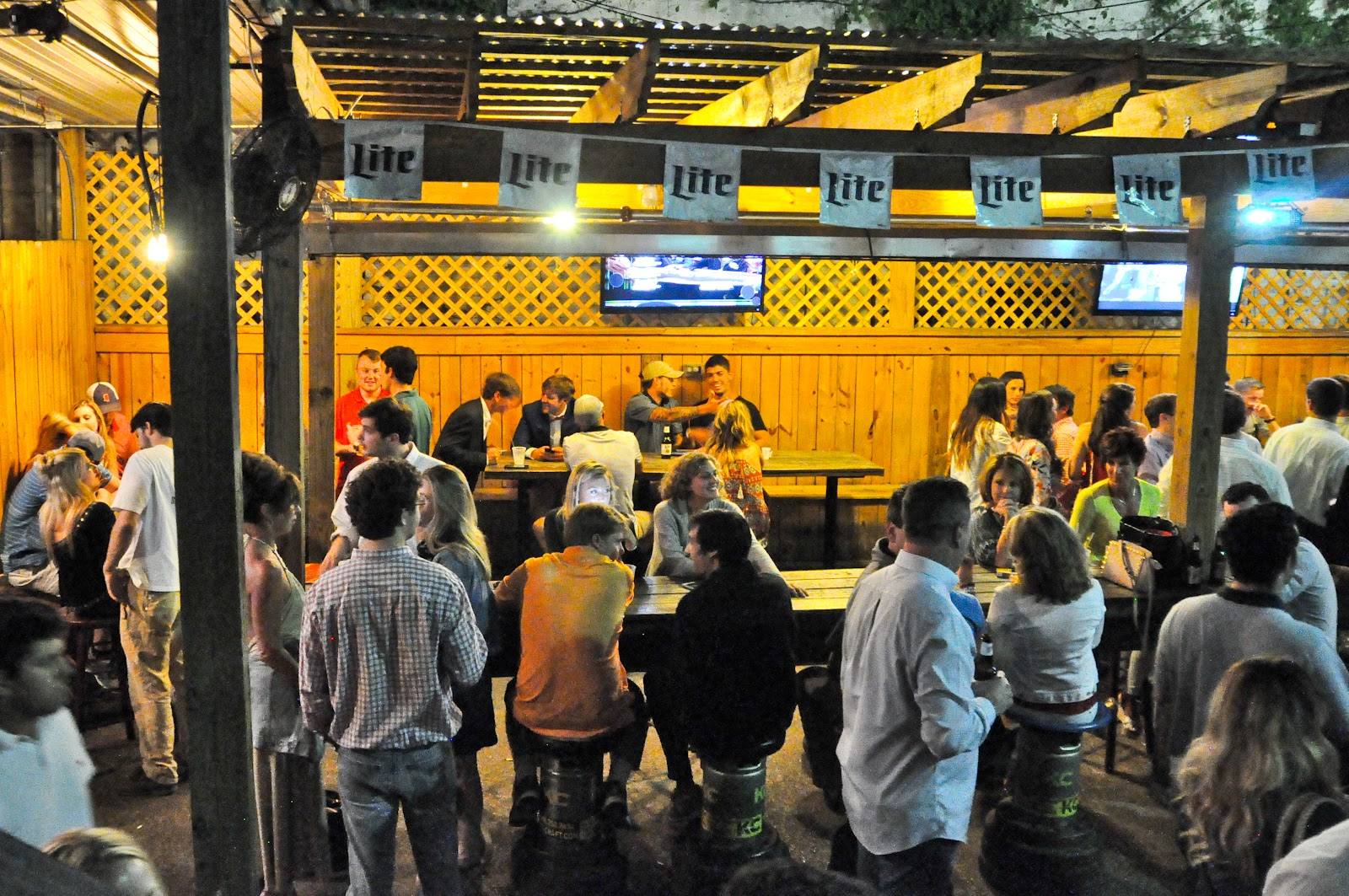 Tables on the Round Table patio under the TVs and beer banners
